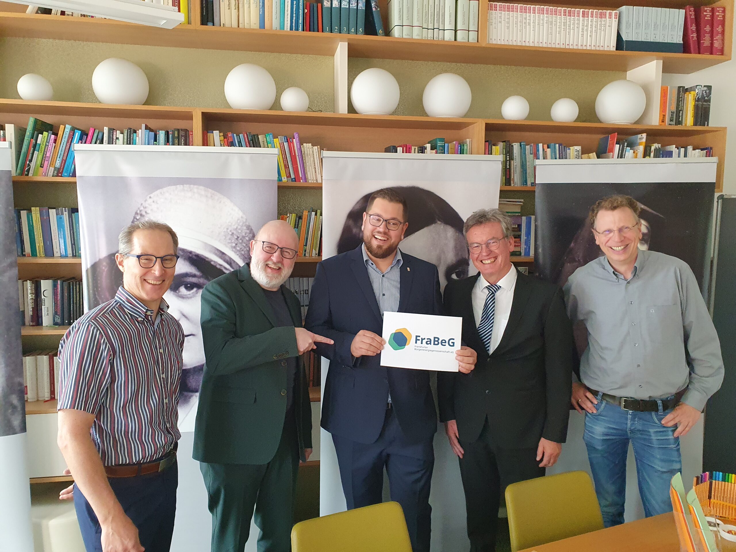 Fünf Personen schauen in die Kamera und lächeln, halten dabei einen Gutschein